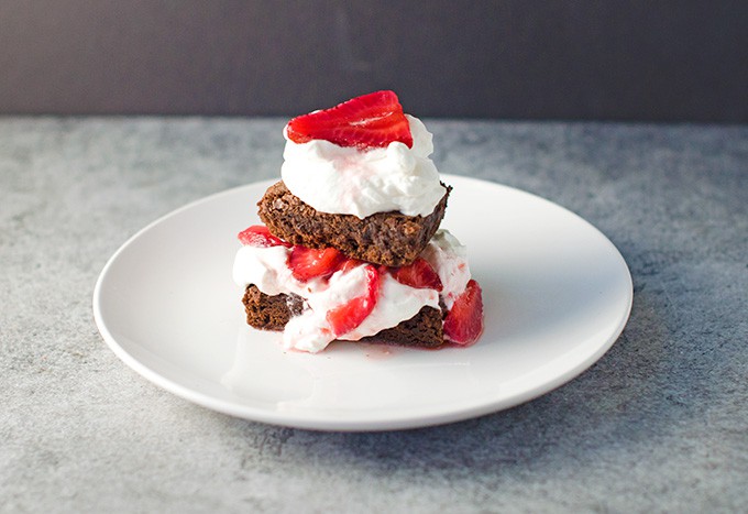 a photo of the sliced brownies being made into a strawberry shortcake with macreated strawberries and whipped cream.