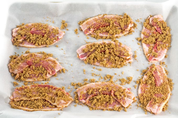 Bacon footballs on baking sheet sprinkled with brown sugar ready to bake