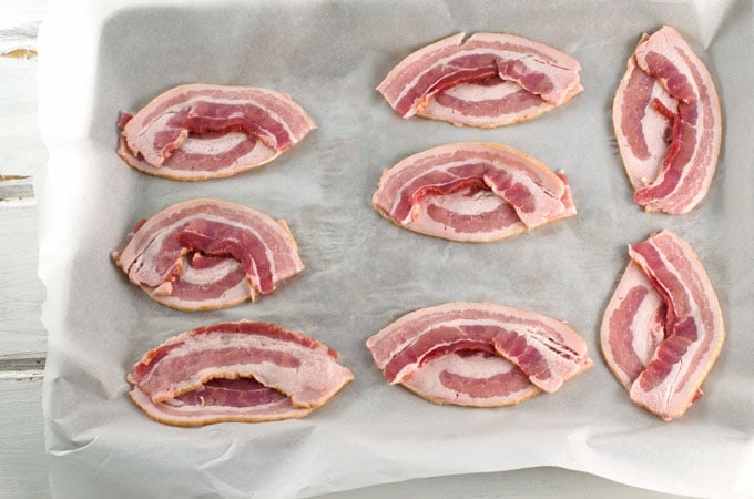 Candied Bacon Footballs Recipe - Bacon Shaped as Footballs on parchment lined baking sheet