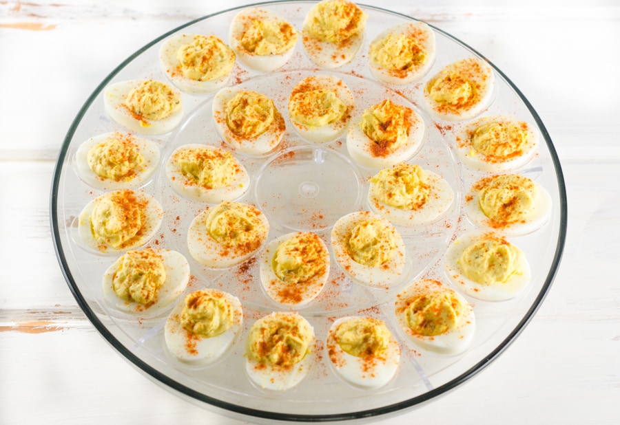 A fill deviled egg platter on a distressed white wood table top